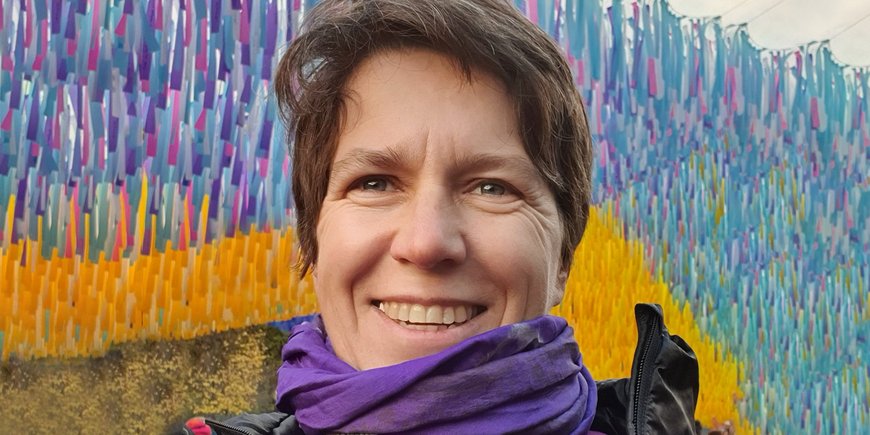Portrait of Kirsten Elger with a colourful background.