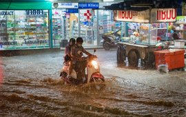 Überflutete Strasse mit Geschäften und Motorradfahrer