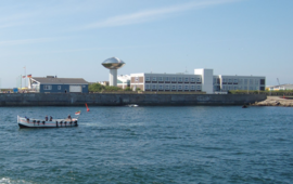 Das Foto zeigt die Biologische Anstalt Helgoland des Alfred Wegener Instituts mit dem Binnenhafen und einem typischen Börteboot.