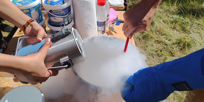 Homemade ice cream is made on a table with liquid nitrogen. Hands, bowl, and it smokes.