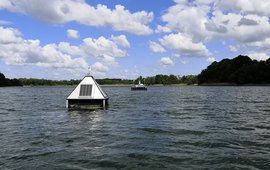 Pyramid-shaped measuring devices float on a lake.