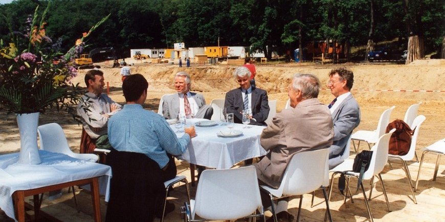 Egon Althaus um einen Tisch sitzend mit Kollegen draußen im Freien auf einem Projekt