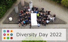 A group of people gathering around the flag for Diversity Day - in the pillar forum on Telegrafenberg.