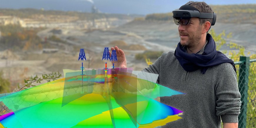 Eine Person steht mit aufgesetzter VR-Brille im Gelände, vor ihm ein digitales Geländemodell, mit dem er gerade interagiert.