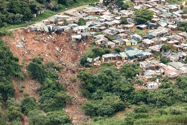 Landslide on a slope directly adjacent to a settlement with small houses.