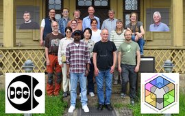 Group photo on the stairs in front of a wooden house; on the right and left the logos of DGG and AG Geomagnetik.