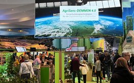 Large screen with Agrisens lettering and a satellite, hung in a hall at the "Grüne Woche" agricultural trade fair.