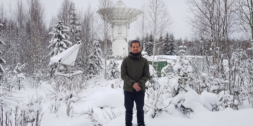 Minghui Xu in einer Schneelandschaft vor dem Metsa̎hovi VGOS-Radioteleskop