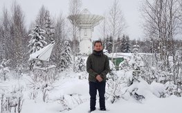 Minghui Xu in a snowy landscape in front of the Metsa̎hovi VGOS radio telescope.