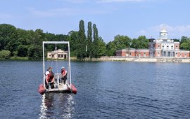 Taking sediment cores at Heiliger See: three persons on a raft, in the background the Neuer Garten with the Marmorpalais.
