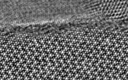 TEM image: below single dots represent the perfect crystal structure in atomic resolution, above the thin disordered amorphous layer. On top, the protective layer.