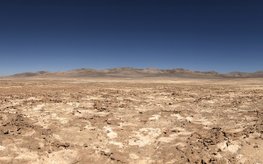 Wüstenlandschaft mit Hügeln und einem ausgetrockneten Seeboden.