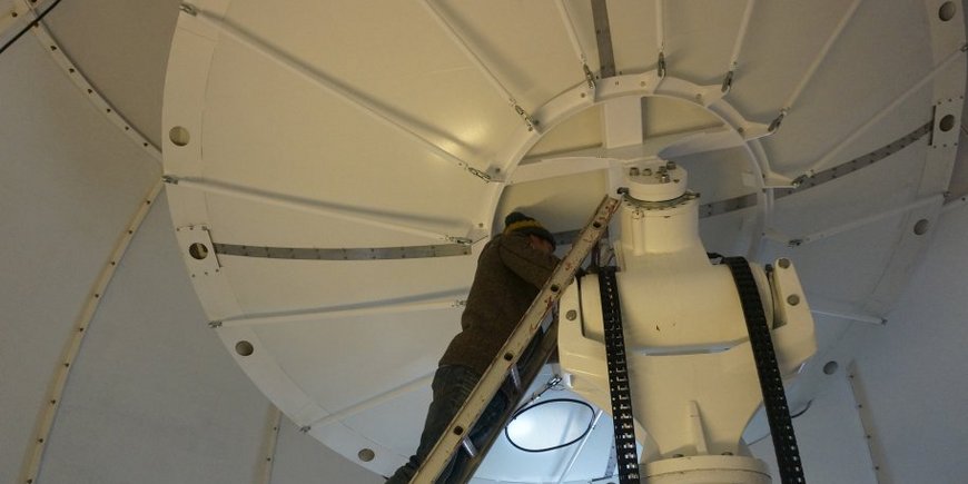 Eine Person im inneren der weißen Kuppel schraubt Apparaturen fest.