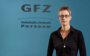 Susanne Buiter in front of a blue wall with GFZ logo