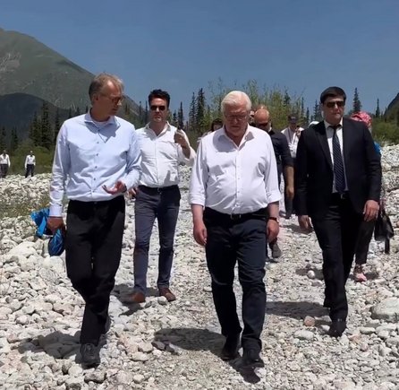 A group of men walking in suit and dress shirt through a dry and rough mountain landscape.