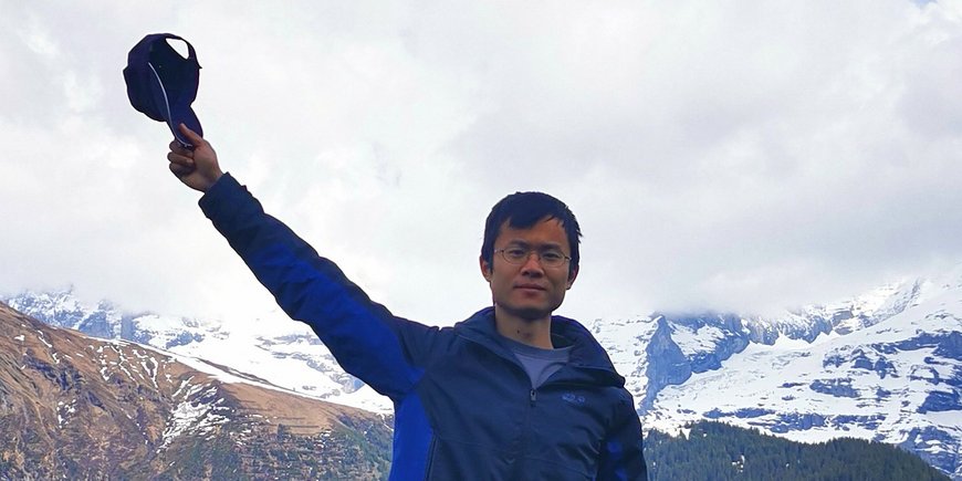 Kai Deng is standing in front of a mountain area