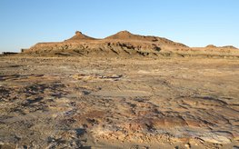 Ausgetrockneter Wüstensee auf der Arabischen Halbinsel mit Gebirgszug im Hintergrund