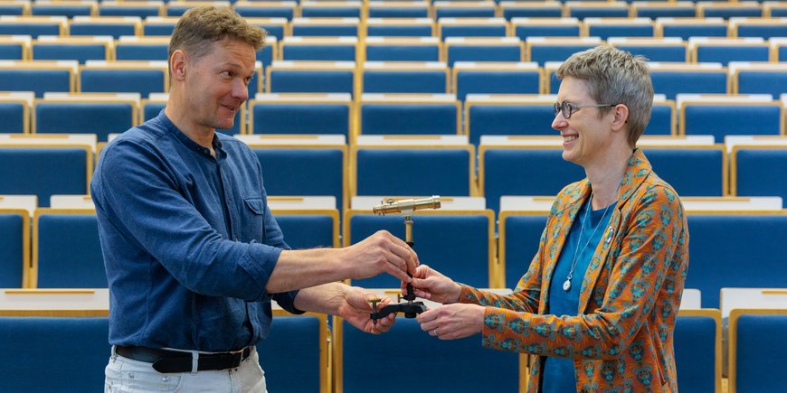Niels Hovius übergibt Susanne Buiter ein optisches Instrument.